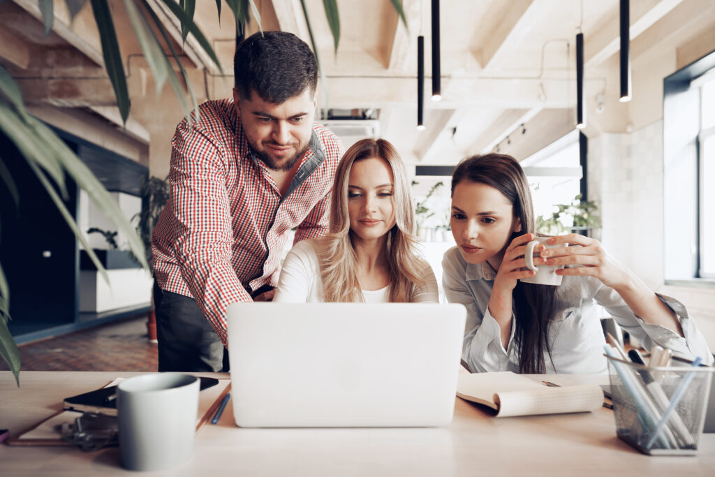 Two female and one male business partners looking at computer screen and discussing their project in office